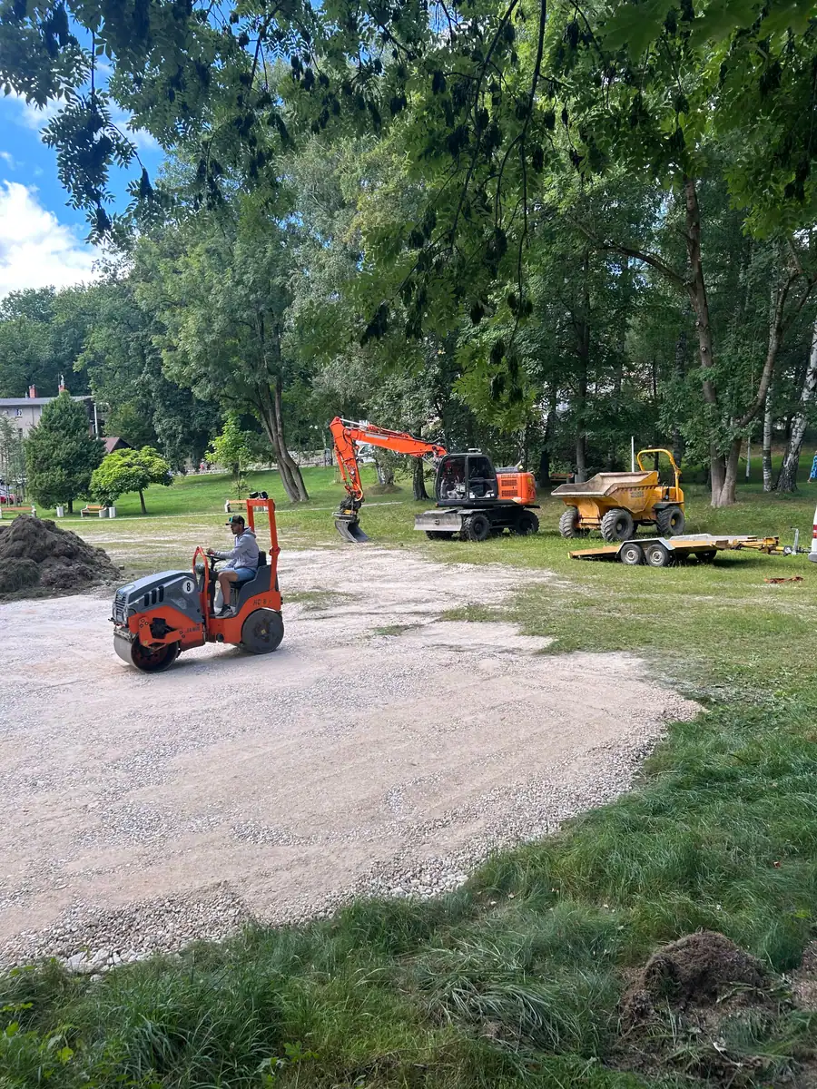 Walec tandemowy HAMM HD8 zagęszcza kruszywo na placu, w tle koparka Hitachi i wozidło Wacker Neuson
